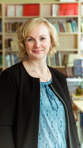 Blond naeratav naine musta jaki ja sinise pluusiga